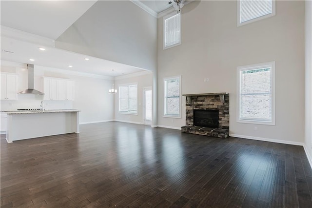 unfurnished living room featuring a ceiling fan, plenty of natural light, crown molding, and a high ceiling