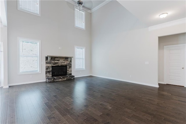 unfurnished living room with baseboards, crown molding, a high ceiling, and dark wood-type flooring