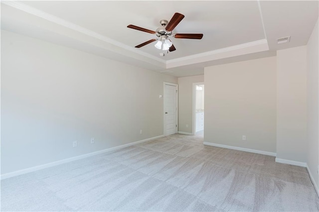 spare room featuring visible vents, baseboards, a raised ceiling, ceiling fan, and light carpet