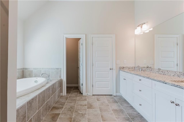 full bath featuring double vanity, a garden tub, a sink, baseboards, and lofted ceiling