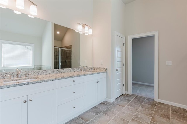 bathroom featuring a sink, double vanity, baseboards, and a shower stall