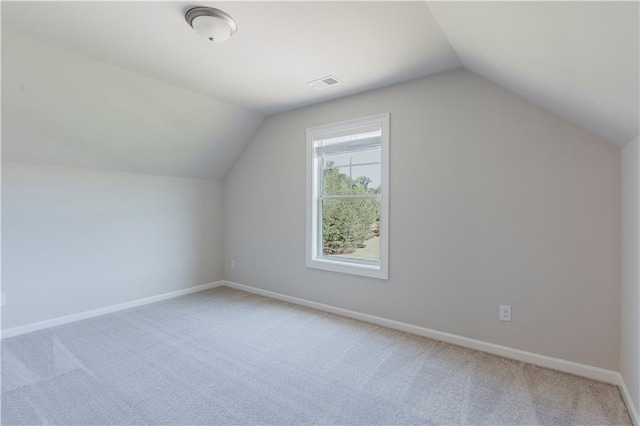 additional living space with vaulted ceiling, light colored carpet, baseboards, and visible vents