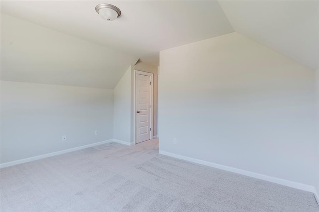 bonus room with light colored carpet, vaulted ceiling, and baseboards