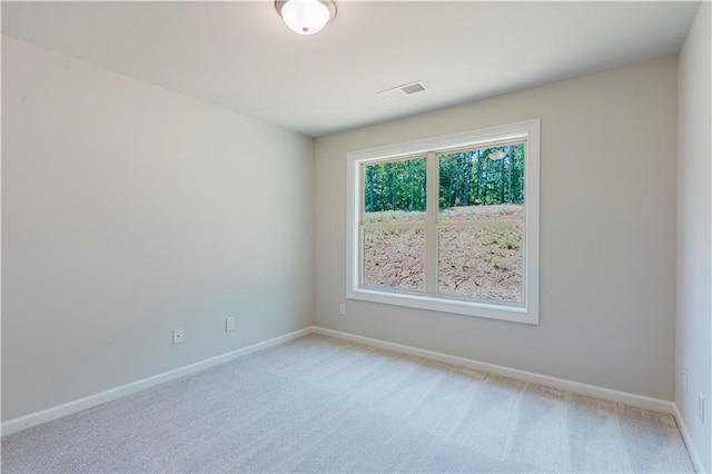 spare room featuring baseboards, visible vents, and light colored carpet