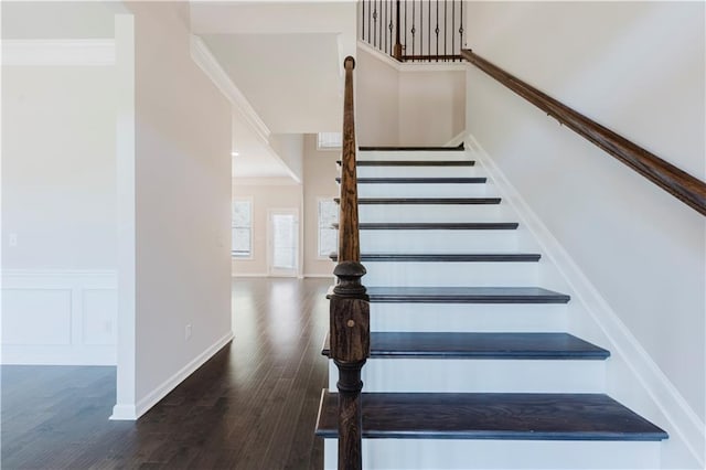 stairs with crown molding and wood finished floors