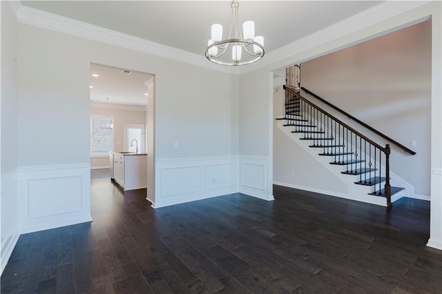 interior space with ornamental molding, an inviting chandelier, wainscoting, dark wood-type flooring, and stairway