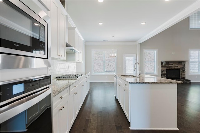 kitchen with a sink, crown molding, dark wood-style flooring, white cabinetry, and appliances with stainless steel finishes