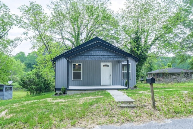 view of front of house featuring covered porch, board and batten siding, and a front yard