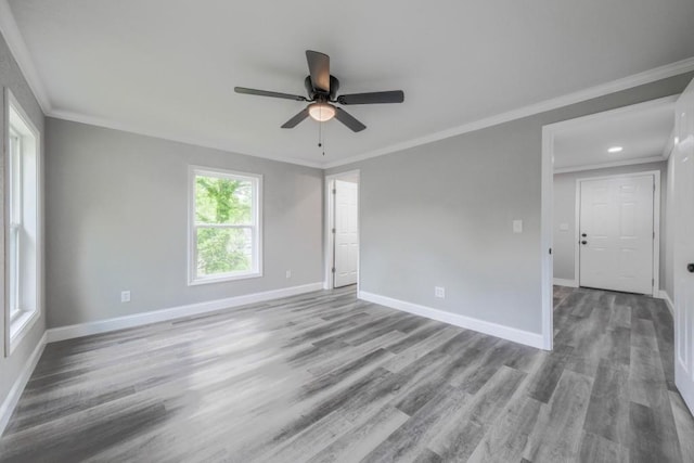 empty room with baseboards, wood finished floors, a ceiling fan, and ornamental molding