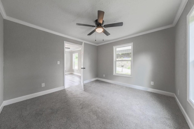 empty room with carpet, ornamental molding, ceiling fan, baseboards, and a textured ceiling
