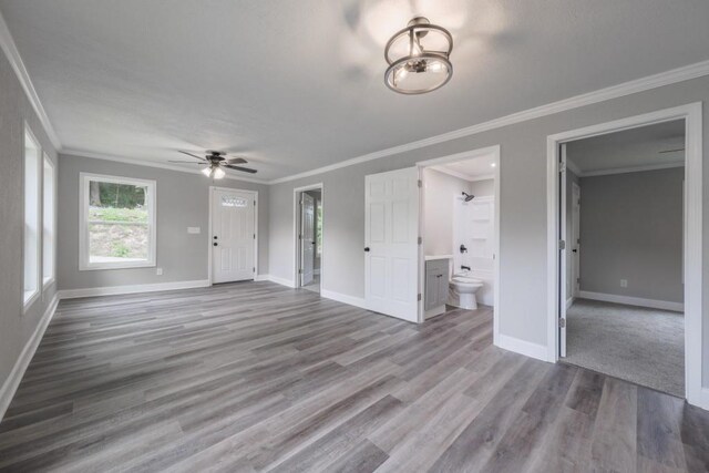 unfurnished living room featuring ceiling fan, baseboards, wood finished floors, and ornamental molding
