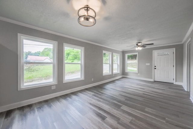 unfurnished living room featuring crown molding, a textured ceiling, dark wood finished floors, baseboards, and ceiling fan