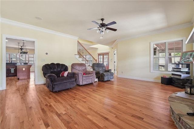 living room with light wood-style floors, ornamental molding, and a ceiling fan