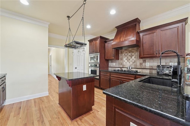 kitchen with stainless steel appliances, custom exhaust hood, light wood finished floors, and a sink