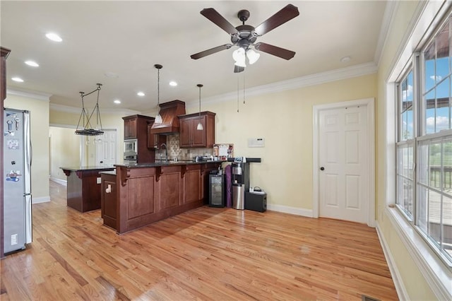 kitchen featuring dark countertops, a kitchen bar, a peninsula, stainless steel appliances, and custom range hood