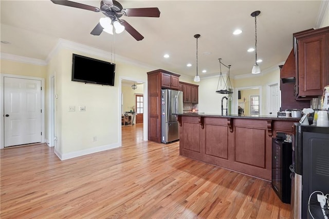 kitchen featuring ceiling fan, dark countertops, freestanding refrigerator, a peninsula, and light wood-style flooring