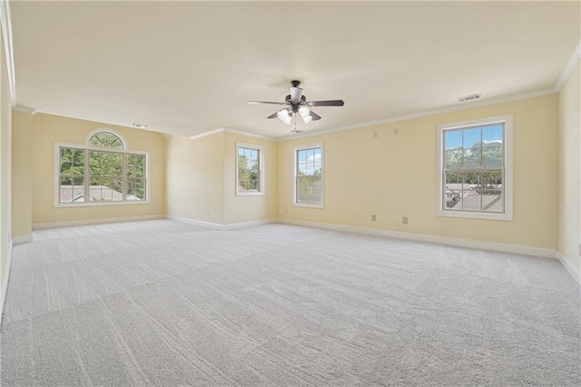 empty room with baseboards, ornamental molding, a ceiling fan, a wealth of natural light, and visible vents