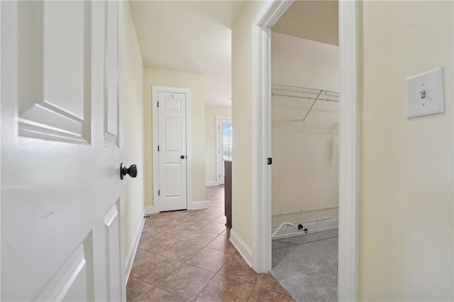 hallway featuring tile patterned floors and baseboards