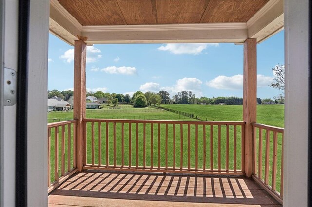 wooden terrace featuring a rural view and a yard