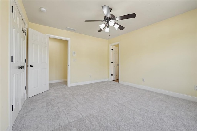 unfurnished bedroom featuring visible vents, light colored carpet, baseboards, and ceiling fan