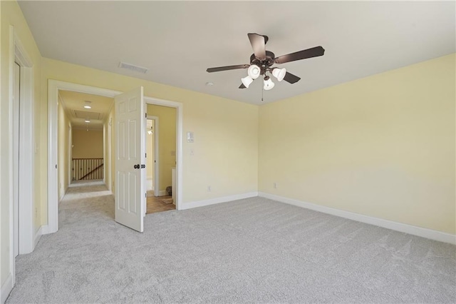 unfurnished bedroom featuring ceiling fan, visible vents, light carpet, attic access, and baseboards