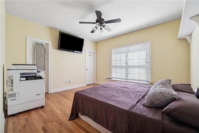 bedroom featuring light wood finished floors, baseboards, and a ceiling fan