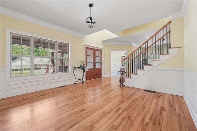 foyer entrance with stairs, french doors, ornamental molding, and wood finished floors