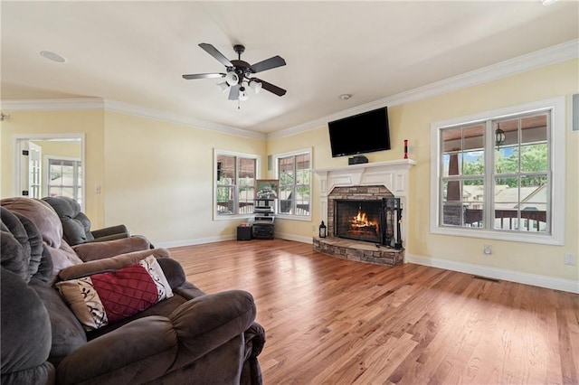 living area with visible vents, ornamental molding, a ceiling fan, a fireplace, and wood finished floors