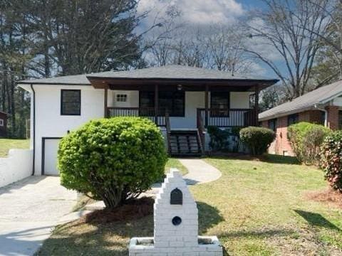 view of front of home with covered porch, a front yard, and a garage