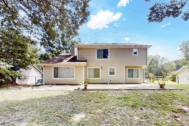 rear view of property with a patio area, a chimney, fence, and a yard