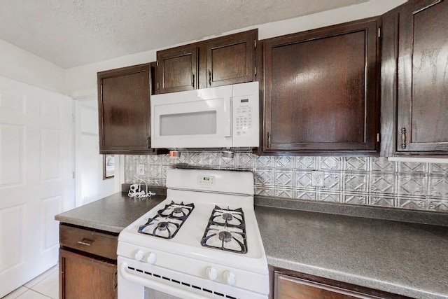 kitchen with dark brown cabinetry, white appliances, decorative backsplash, dark countertops, and a textured ceiling