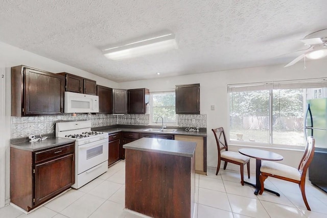 kitchen featuring a sink, dark brown cabinets, white appliances, and a kitchen island