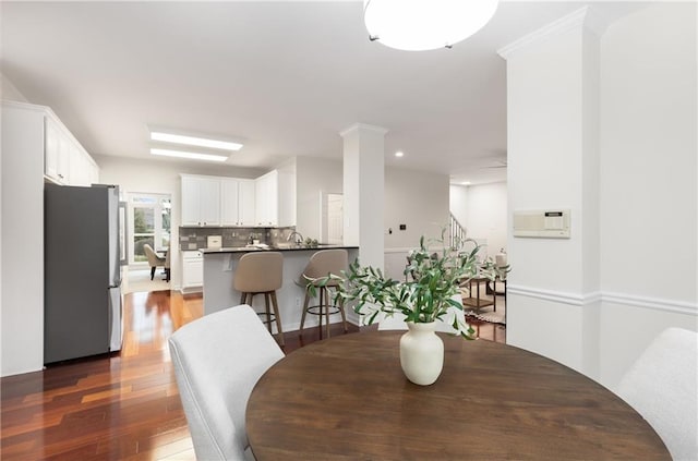 dining space featuring dark wood-type flooring, recessed lighting, and ornate columns