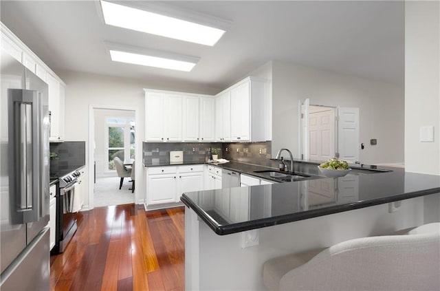 kitchen with stainless steel appliances, a breakfast bar, a peninsula, a sink, and white cabinets