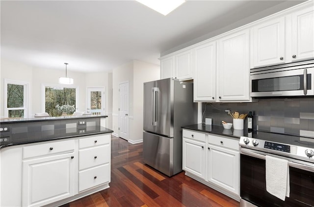 kitchen with tasteful backsplash, white cabinets, dark wood finished floors, dark countertops, and stainless steel appliances