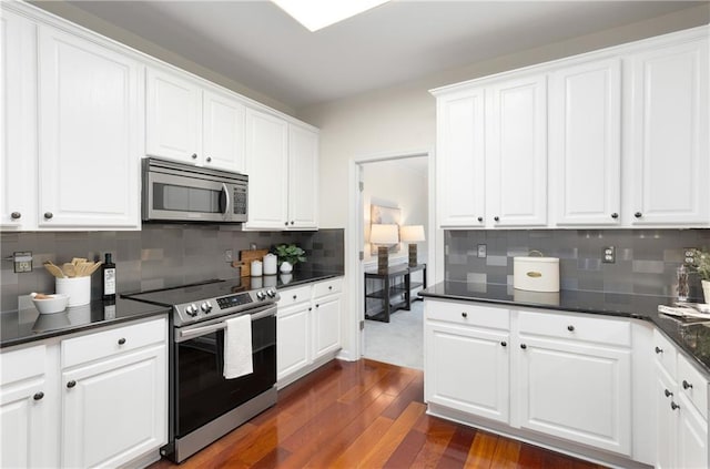 kitchen with dark wood-style floors, appliances with stainless steel finishes, dark countertops, and white cabinetry