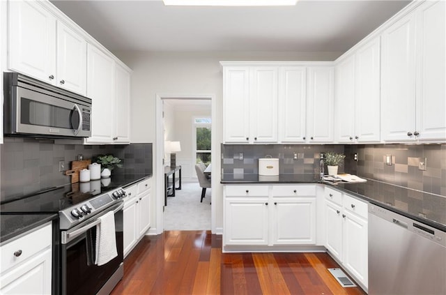 kitchen with appliances with stainless steel finishes, dark wood-style flooring, visible vents, and white cabinetry