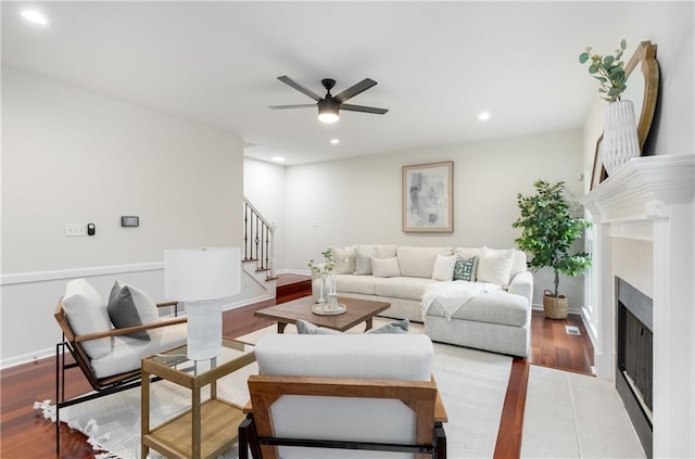 living area with recessed lighting, a fireplace with flush hearth, ceiling fan, baseboards, and stairs