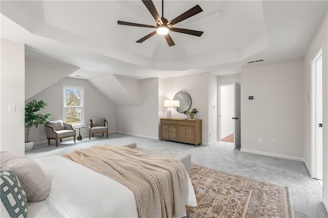 bedroom with light colored carpet, a ceiling fan, baseboards, visible vents, and a tray ceiling