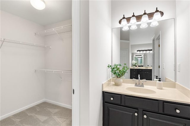 full bathroom featuring a walk in closet, vanity, and baseboards