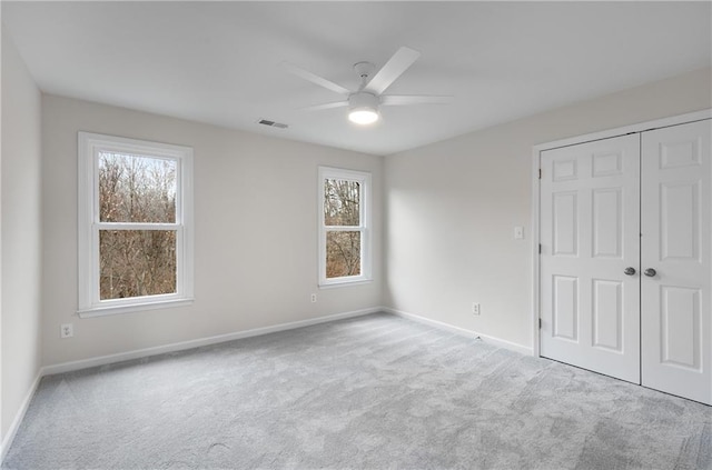 unfurnished bedroom with a closet, multiple windows, carpet flooring, and baseboards