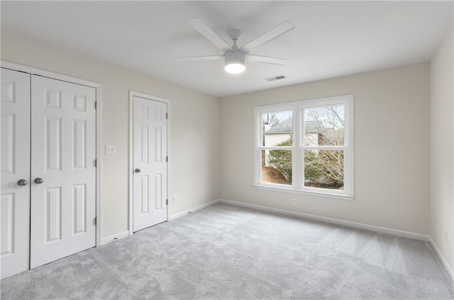 unfurnished bedroom with a ceiling fan, carpet, visible vents, and baseboards