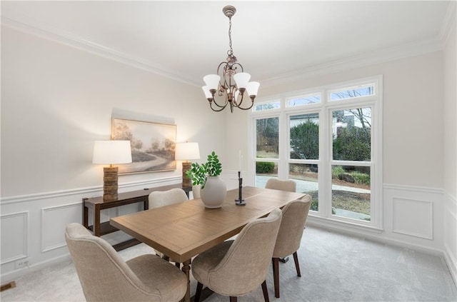 dining room featuring light carpet, ornamental molding, wainscoting, and an inviting chandelier