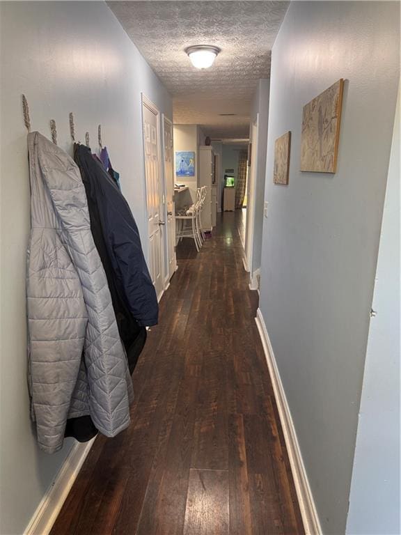 hall featuring dark wood-type flooring and a textured ceiling