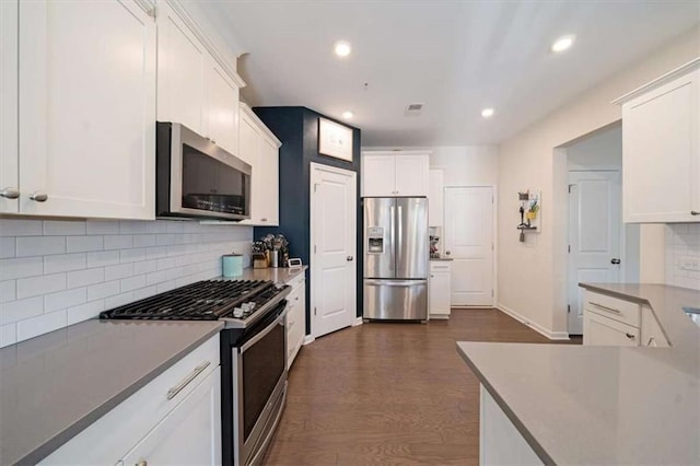 kitchen featuring stainless steel appliances, white cabinetry, dark hardwood / wood-style floors, and decorative backsplash