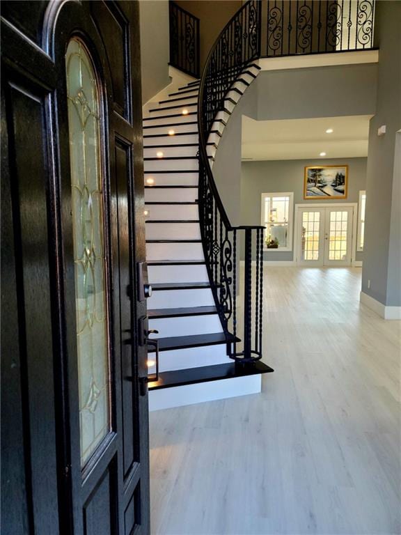 stairway with a high ceiling, french doors, and hardwood / wood-style flooring