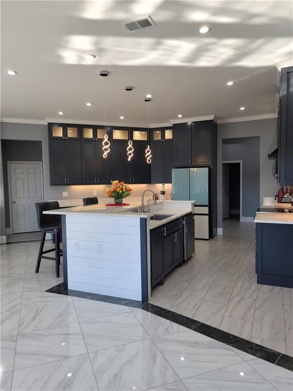 kitchen with pendant lighting, an island with sink, ornamental molding, and light tile patterned floors