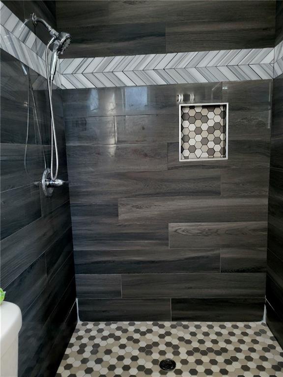 bathroom featuring a tile shower and toilet