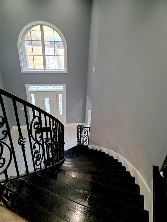 staircase with hardwood / wood-style floors and a high ceiling