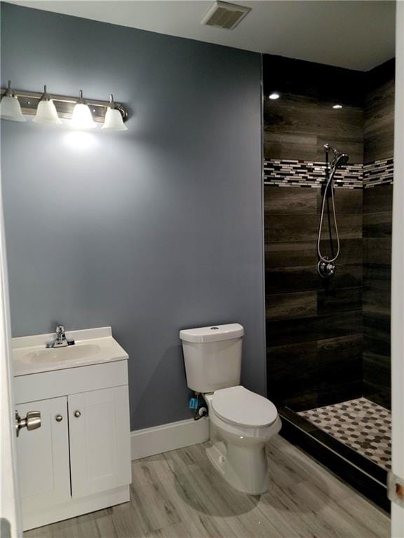 bathroom with vanity, tiled shower, wood-type flooring, and toilet